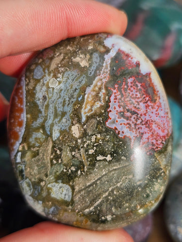 hand holding ocean jasper palm stone for meditation